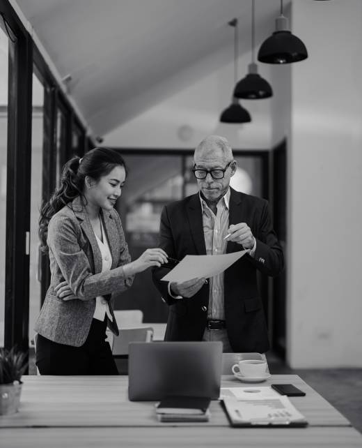 Senior businessman and businesswoman reviewing contract and discussing terms of agreement in modern office, they are working together on a new project Senior businessman and businesswoman reviewing contract and discussing terms of agreement in modern office, they are working together on a new project